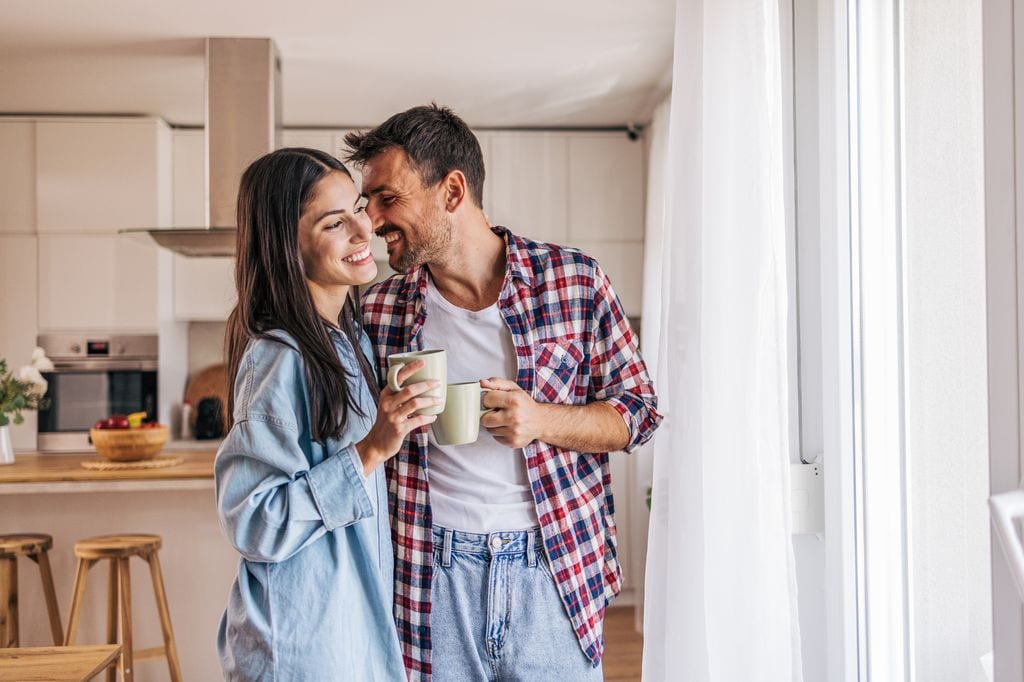 pareja sonriente tomando un café en la cocina