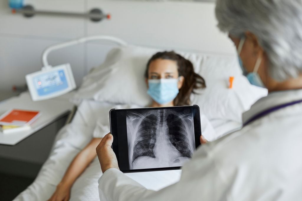 paciente ingresada con un doctor mirando una radiografía de torax