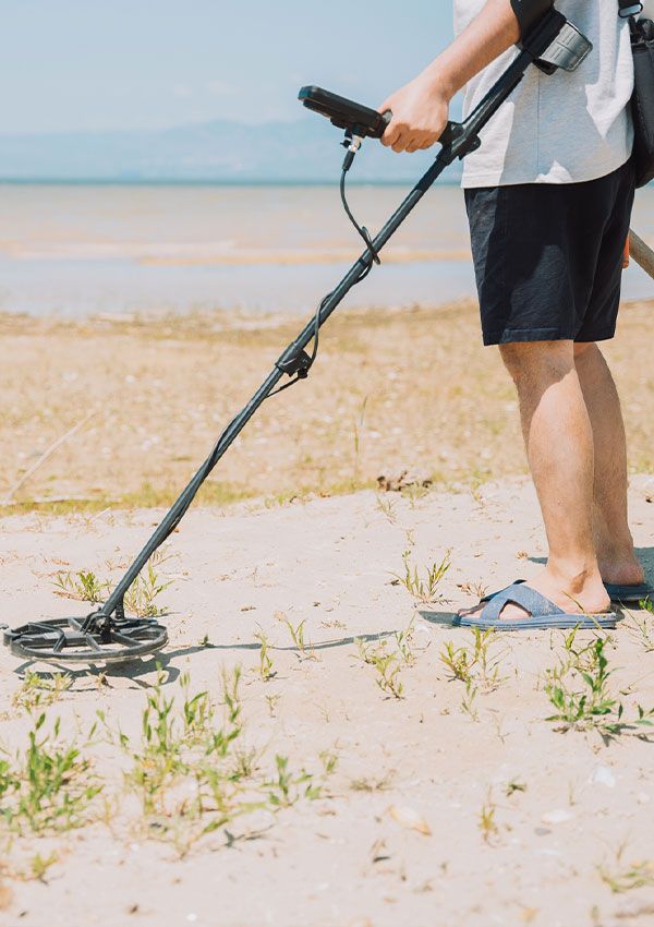 Un hombre usando un detector de metales en la playa