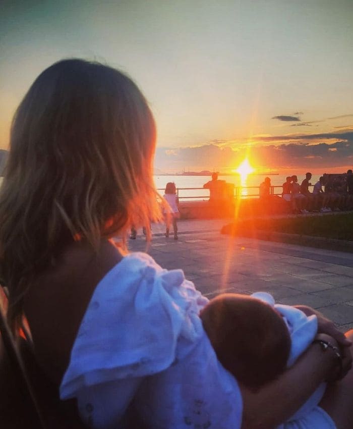 Andrea mirando un atardecer con su hija en brazos