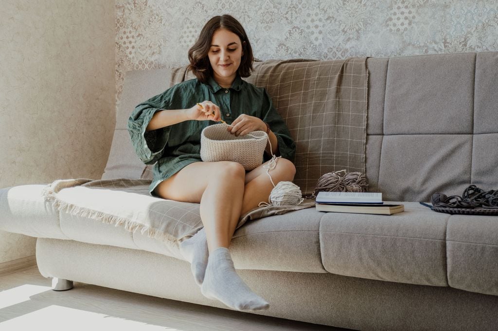 mujer haciendo punto en el sofá de su casa