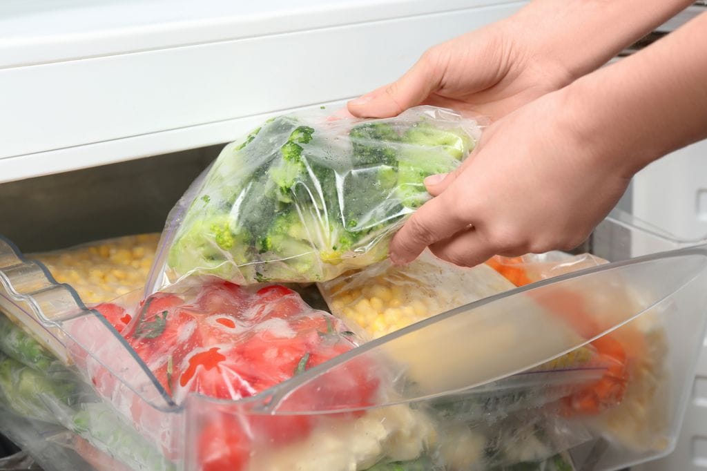 Colocando bolsas con verduras en el congelador