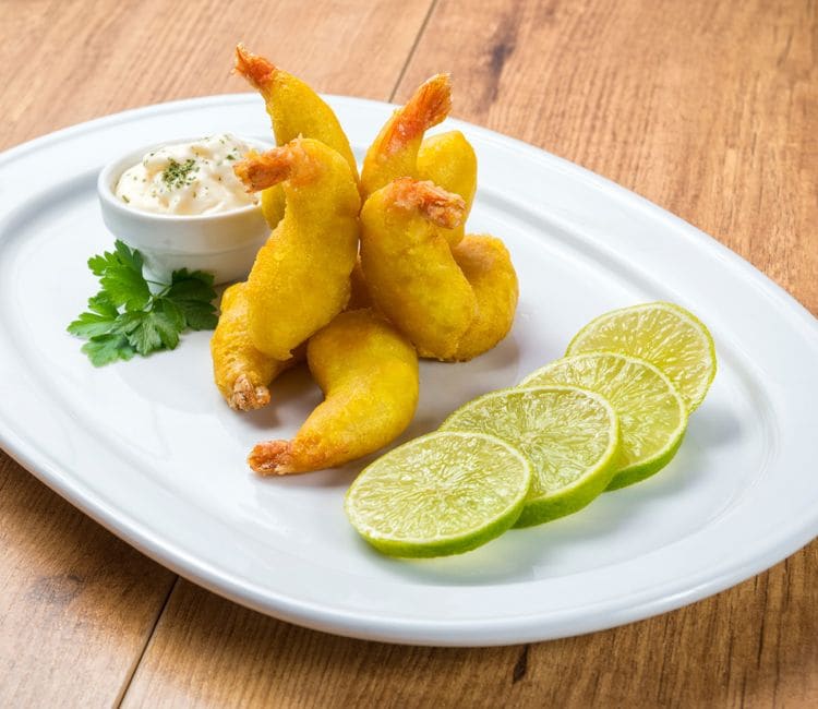 Plato con gambas a la gabardina, un bol con mayonesa y rodajas de lima