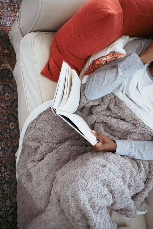 Persona leyendo un libro con una manta en las piernas