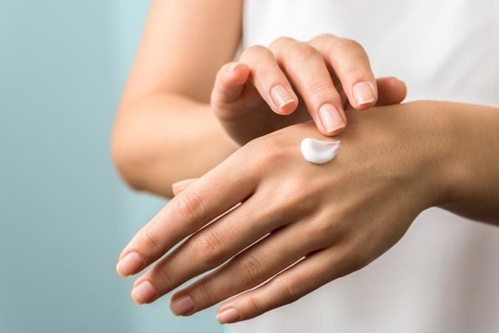 mujer aplicando crema en sus manos