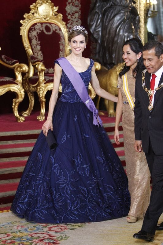 Doña Letizia estrenó un vestido muy diferente a los que había lucido en las últimas cenas de gala. Un diseño de Felipe Varela con mucho volumen en la falda, en tul azul noche, bordado de hojas con hilo y cristal marino, prusia y zafiro. Con un 'pochette' de la misma casa en raso azul noche
