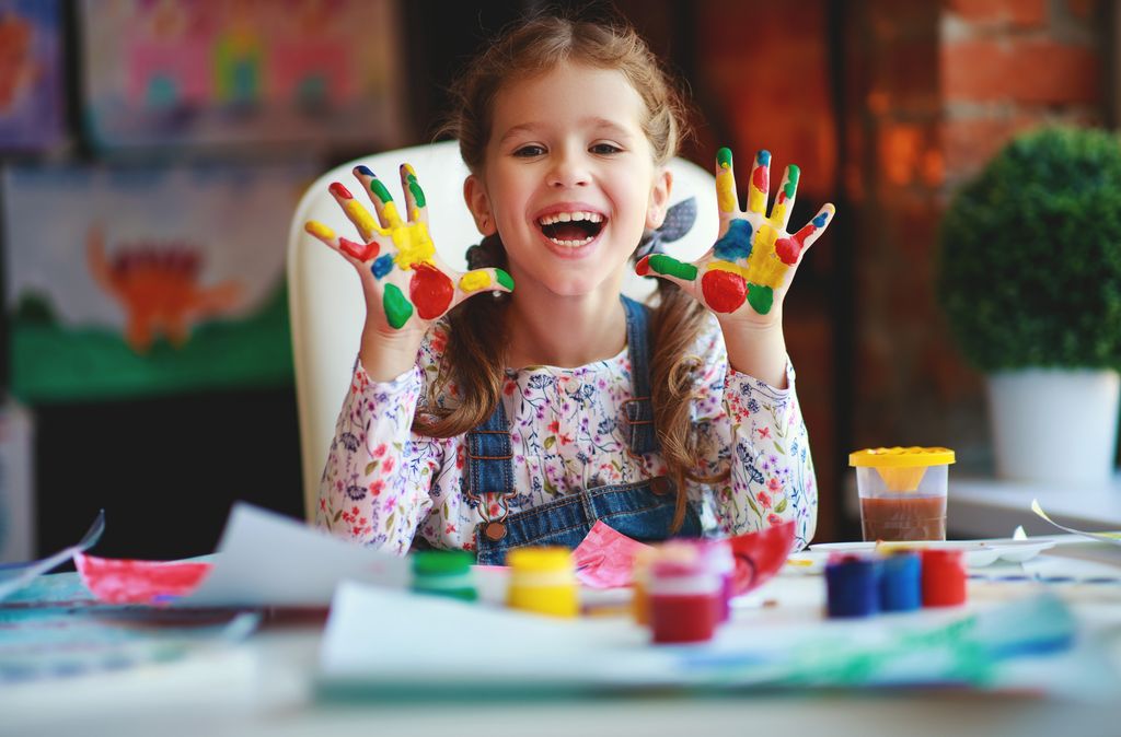 Niña con las manos pintadas jugando