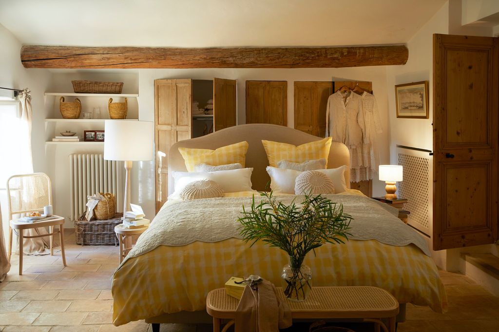 Dormitorio con viga de madera y cama con ropa de cama de cuadros.