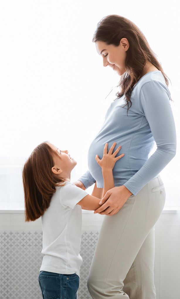 Mamá embarazada con su hija mayor acariciando su tripa