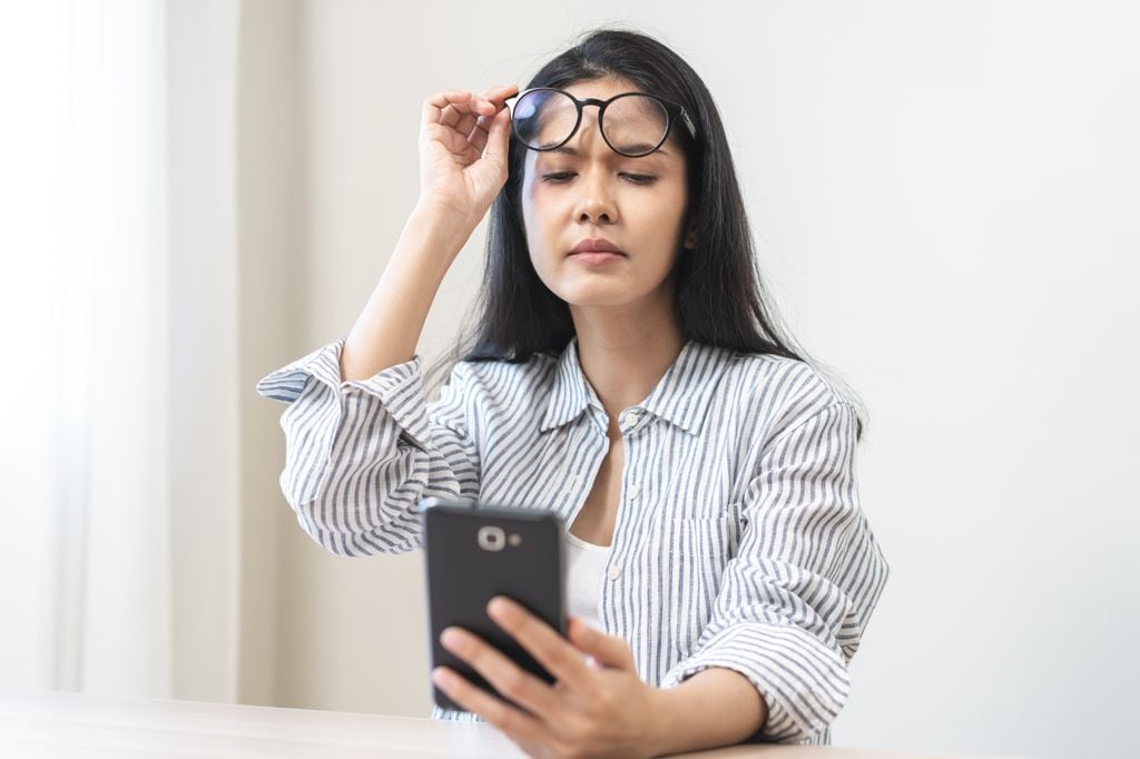 mujer mirando su móvil levantándose las gafas