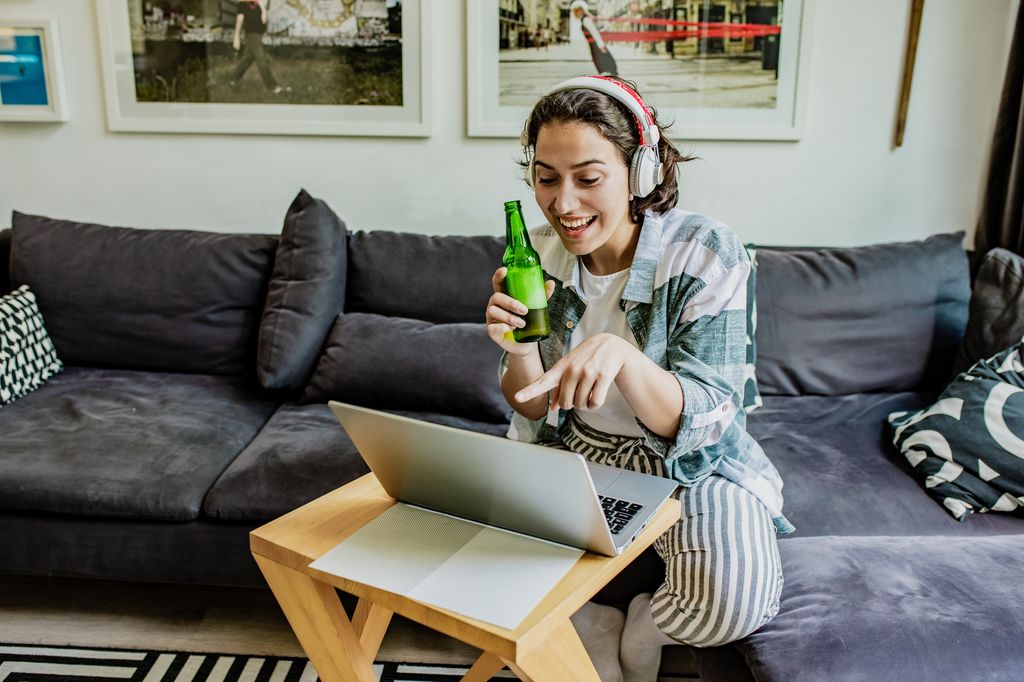 mujer bebiendo cerveza mientras hace una videollamada