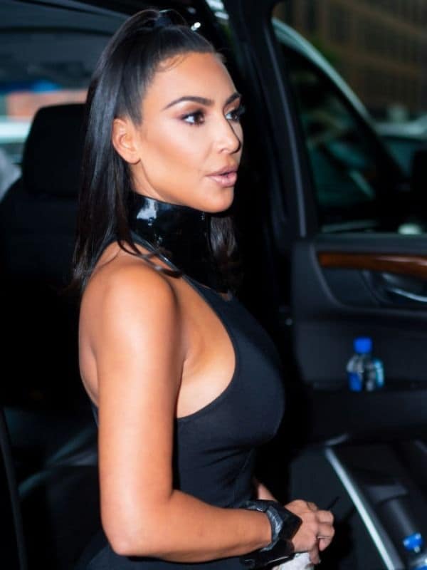 Kim Kardashian de perfil con pony casual a la mitad y vestido negro 