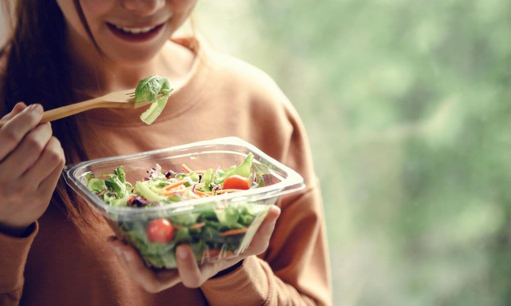 mujer comiendo plato saludable