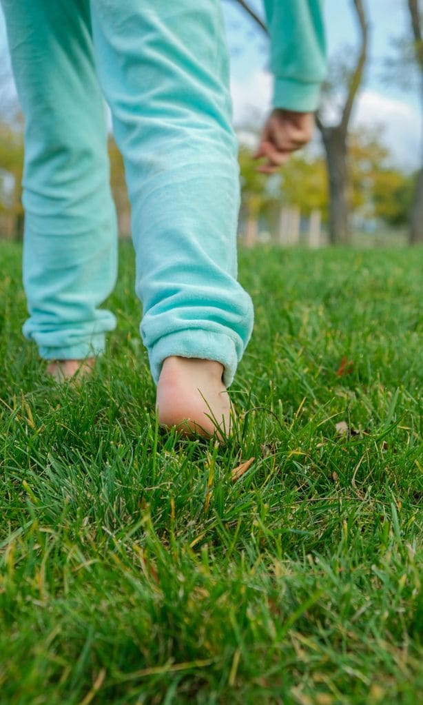 Niño caminando descalzo sobre césped