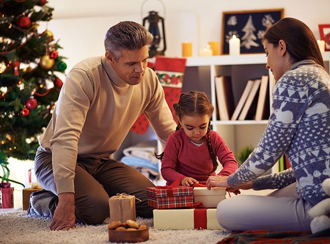 Familia abriendo regalos junto al árbol