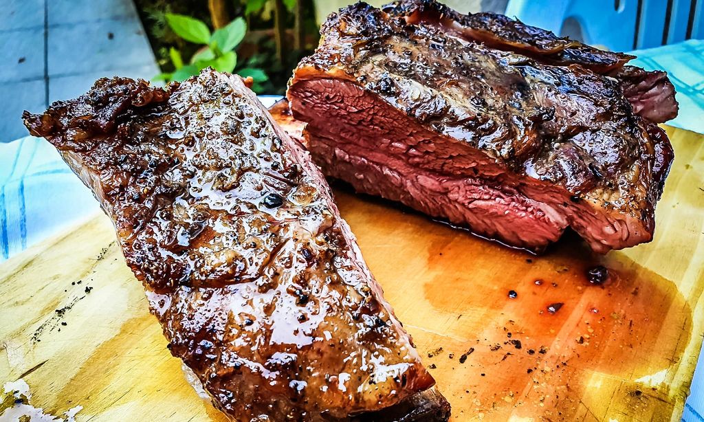 Close-up of argentine grilled ribs (asado argentino or costillar) on a wooden board