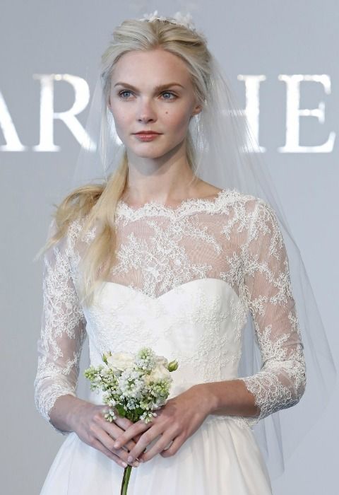 Una novia clásica, con vestido de manga francesa en encaje y cuello barco ribeteado con blondas, de Marchesa. La firma completa el look con un velo de aire fifties a la cadera, que no cubre el rostro y se prende con una diadema. 