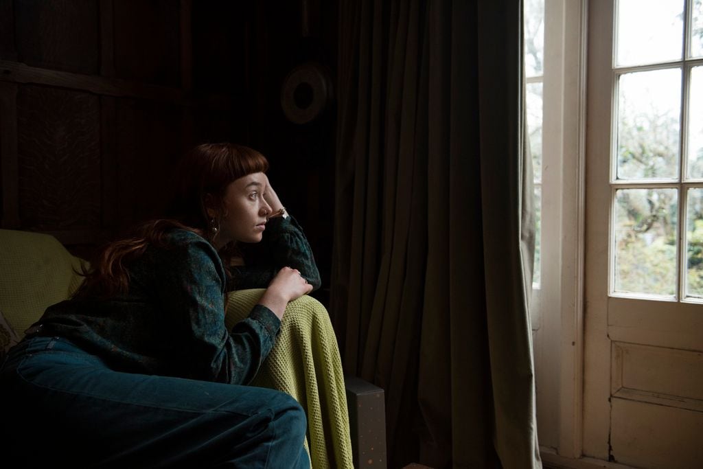 mujer melancólica mirando por la ventana