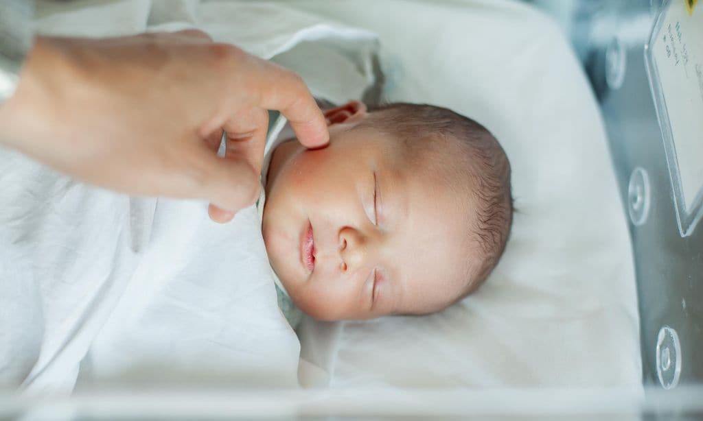 Newborn baby boy asleep in hospital bassinet