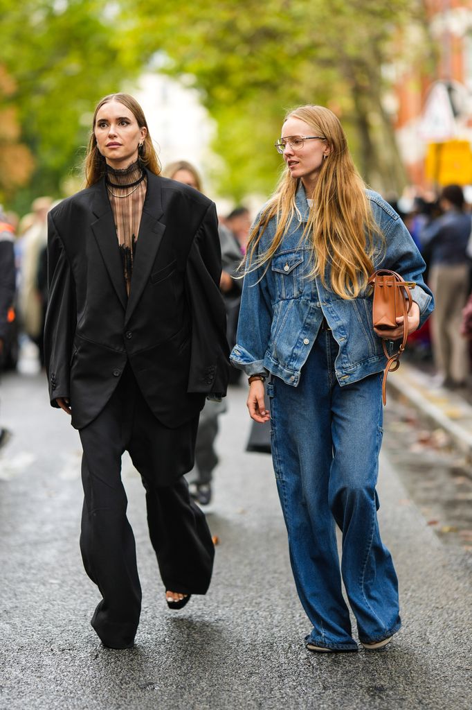 Pernille Teisbaek lleva pendientes de oro y diamantes, una blusa negra de tul de cuello alto / mangas largas, una chaqueta blazer oversize negra, pantalones de traje grandes negros, zapatos de plataforma de terciopelo negro, Una invitada lleva gafas, una camiseta blanca, una chaqueta vaquera azul desteñida grande, pantalones vaqueros azules grandes, un bolso Kelly de cuero camel brillante de Hermes, anillos de oro, fuera de Valentino, durante la Semana de la Moda de París - Ropa de mujer Primavera/Verano 2023, el 02 de octubre de 2022 en París, Francia. 