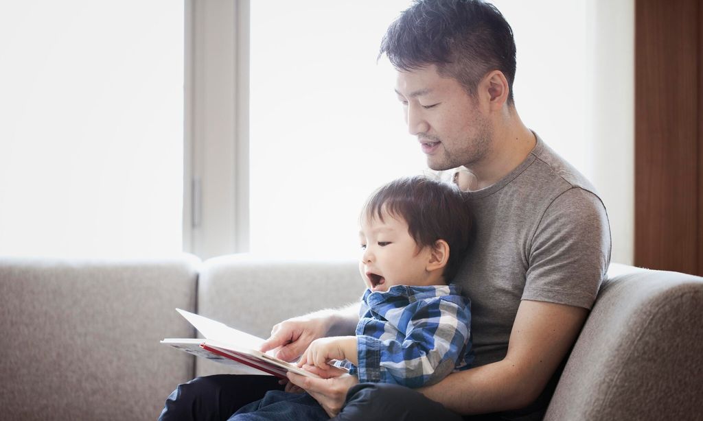 father and son reading a book together