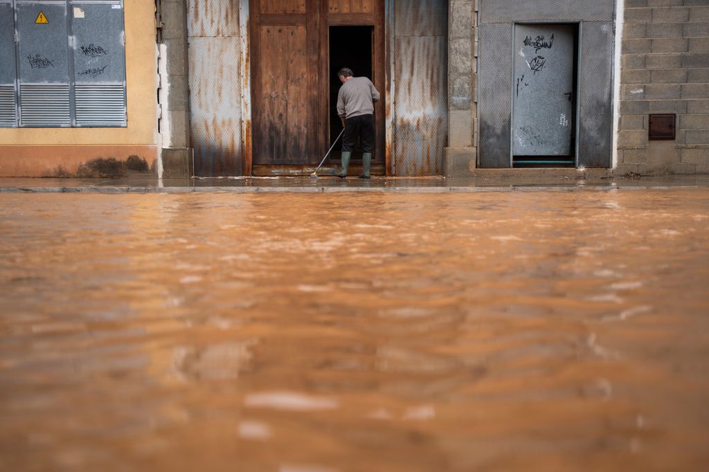 LLOMBAI, VALENCIA VALENCIAN COM, SPAIN - OCTOBER 29: A man cleans mud from his driveway, on 29 October, 2024 in Llombai, Valencia, Valencian Community, Spain. The Emergency Coordination Center (CCE) has raised to red the alert level for rainfall throughout the coast and inland north of Valencia, where the orange alert was set. Thus, the ECC has updated the emergency plans for the DANA that affects this Tuesday, October 29, the Valencian Community, and that early in the morning established the red level only for the south coast of Valencia. (Photo By Jorge Gil/Europa Press via Getty Images)