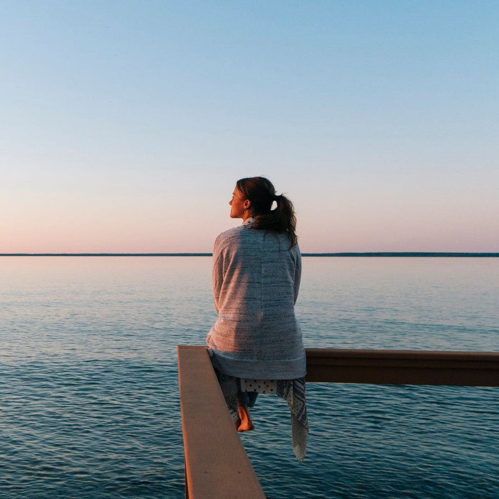 Young woman sitting on edge looks out at view