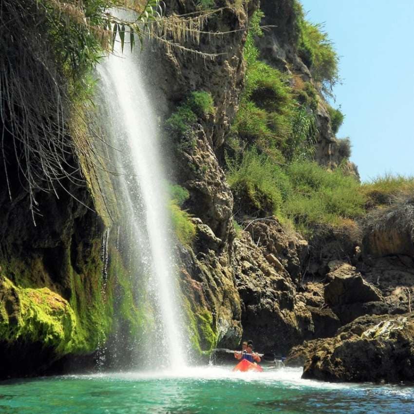 Kayak bajo la cascada en los acantilados de Maro.