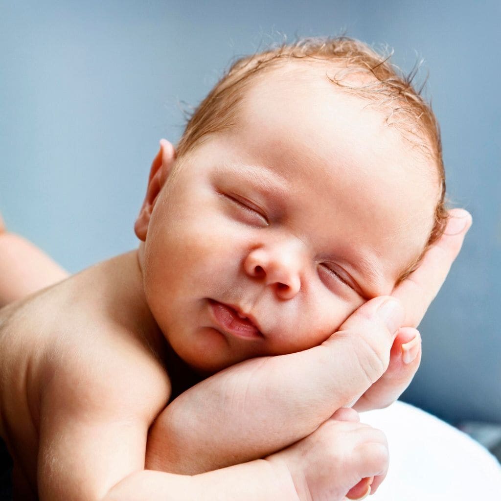 Blissfully sleeping baby cradled in mothers hands