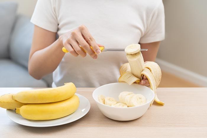 mujer cortando un plátano