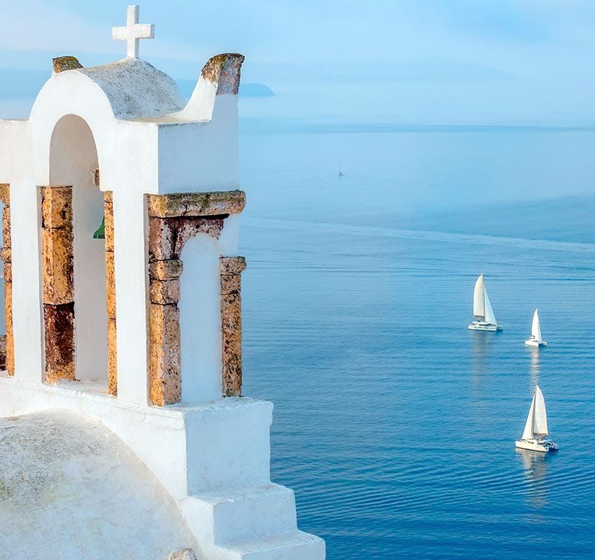 Veleros navegando frente a la isla griega de Santorini