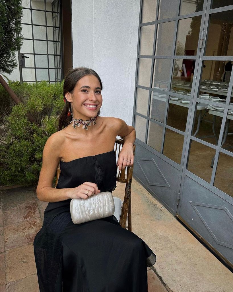 Vestido negro, choker y bolso de mano 