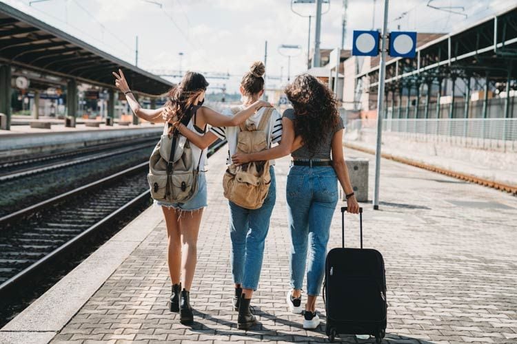 Amigas en la estación del tren con maletas