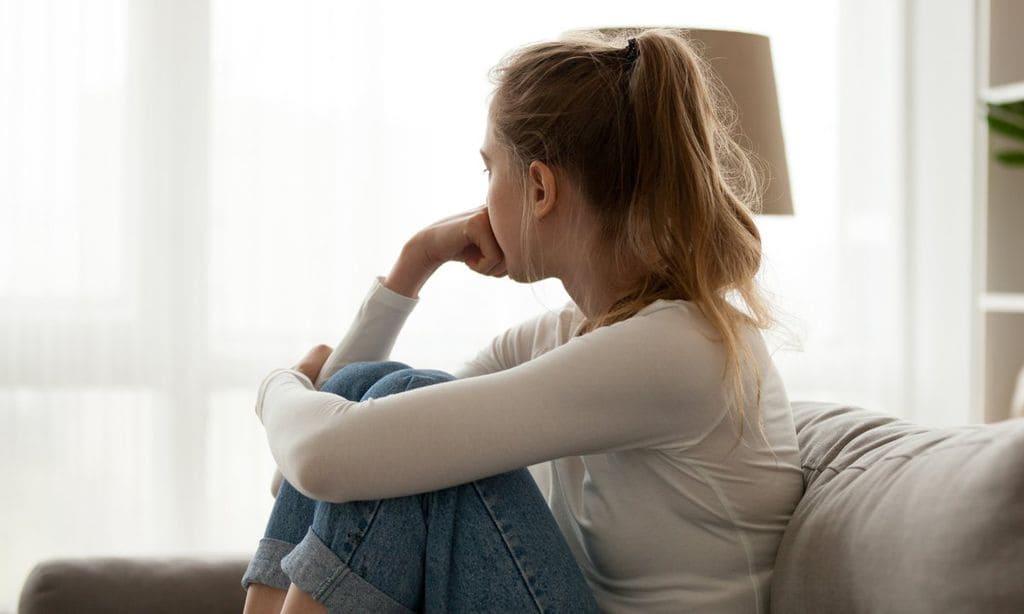 Upset woman sitting on couch alone at home