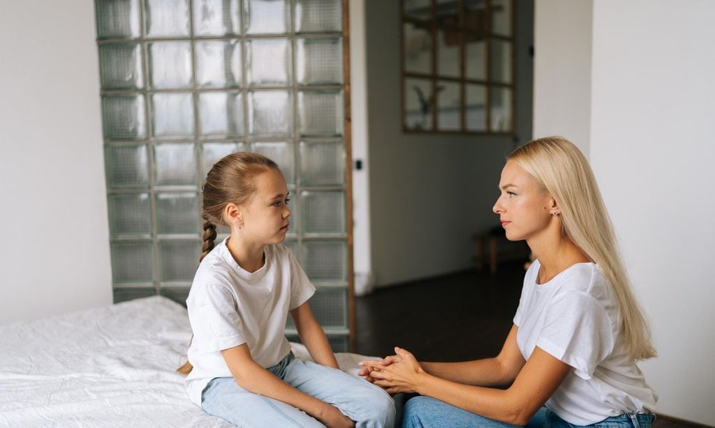 madre hablando con su hija sentada sobre la cama