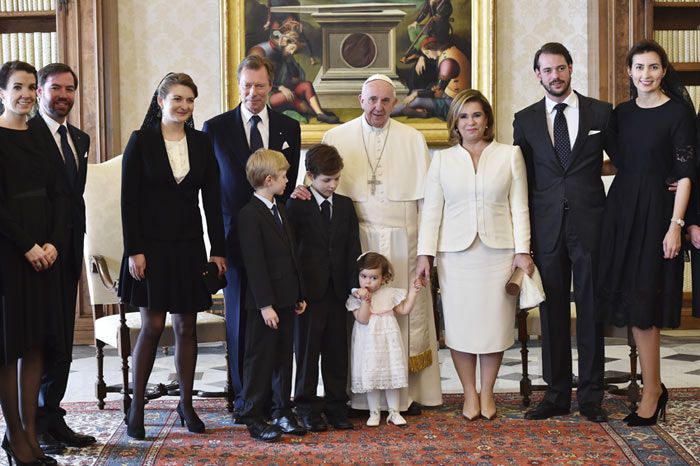 La hija del príncipe Félix y la princesa Claire fue la viva imagen de la ternura con un vestido blanco de volantes, jaretas y puntillas con lazo rosa, unas bailarinas de pulsera y unos rizos de azabache
