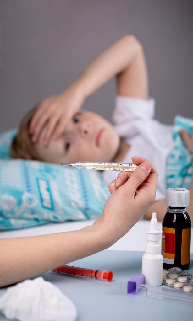 Niña con fiebre y mesa con medicamentos