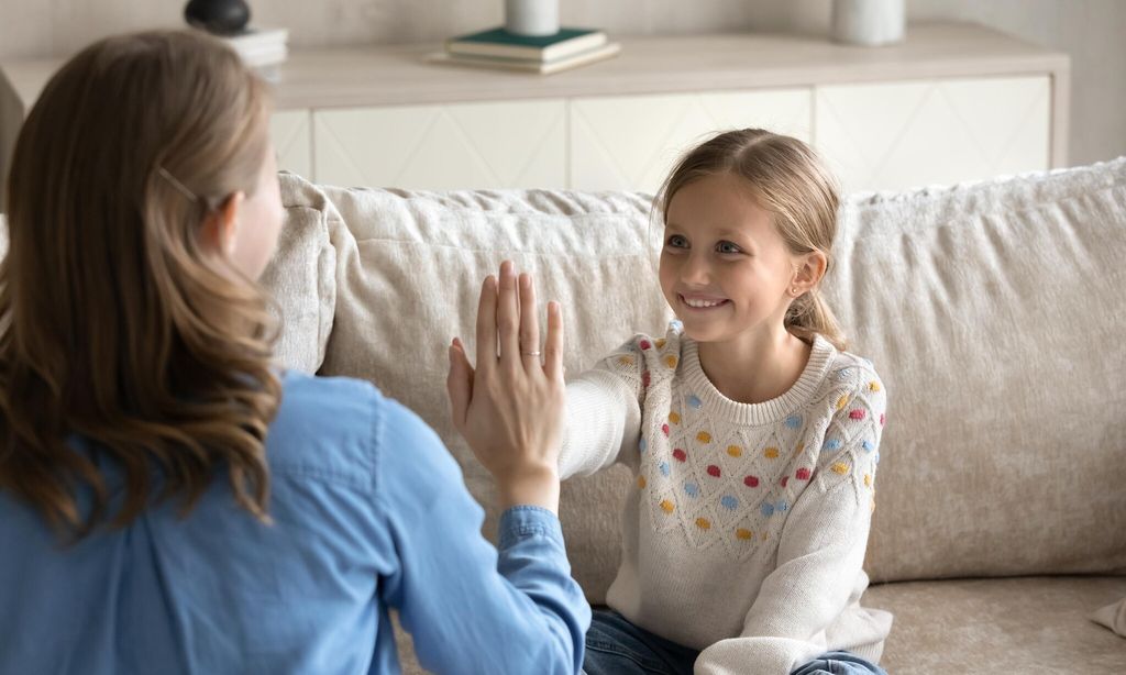 professional female speech therapist praising little patient for success 