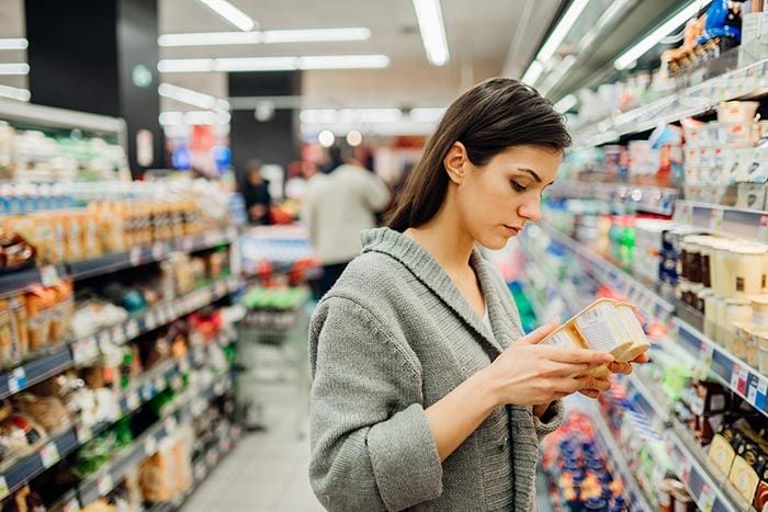 mujer mirando la etiqueta de un producto en el supermercado