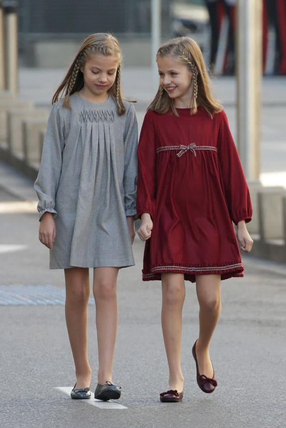 Las niñas, que iban peinadas igual, llevaban vestidos similares en diferentes tonos. La Princesa de Asturias, en granate y con bailarinas del mismo color de Pretty Ballerinas, y la infanta Sofía, en gris y también con bailarinas de la misma firma
