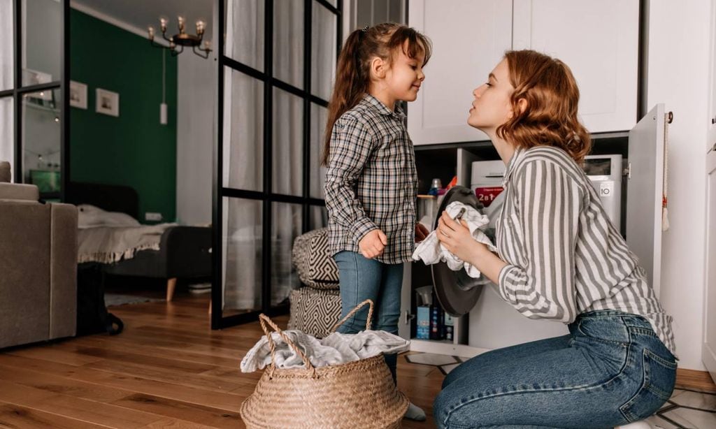 mujer con su hija haciendo la colada mientras conversan