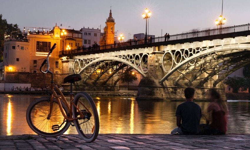 Jóvenes junto al puente de Triana, en Sevilla
