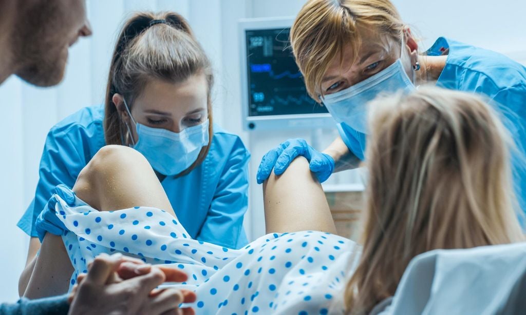 mujer de parto en un hospital con equipo m dico y acompa ante