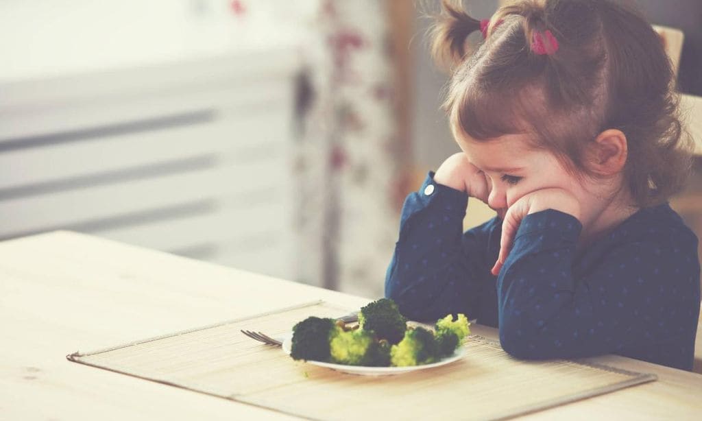 ni a con plato de brocoli en la mesa