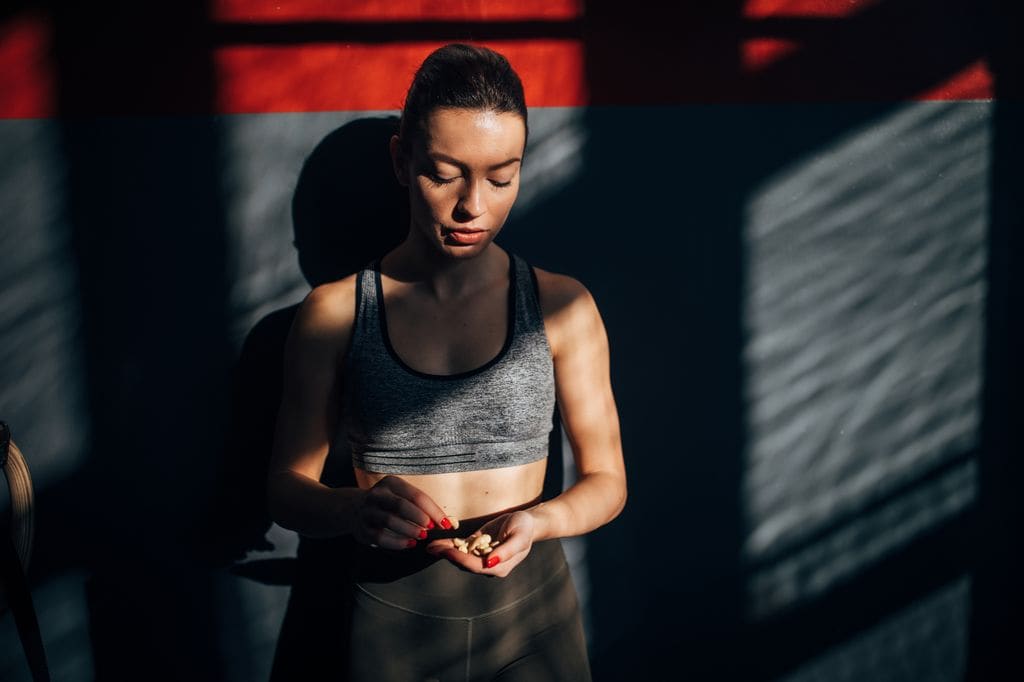 mujer deportista comiendo frutos secos después de un entrenamiento en el gimnasio