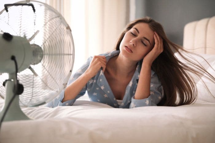 chica en la cama con un ventilador