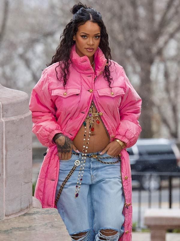 Rihanna con pantalones vaqueros y plumas rosa mostrando su embarazo