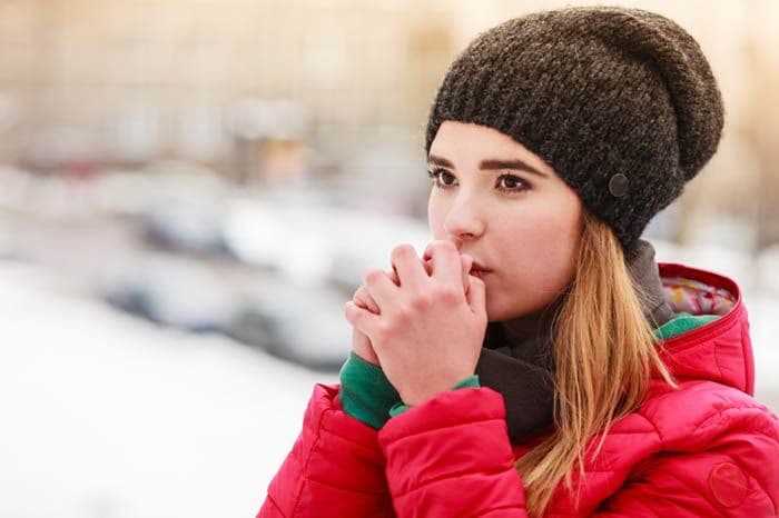 mujer calentando sus manos en invierno