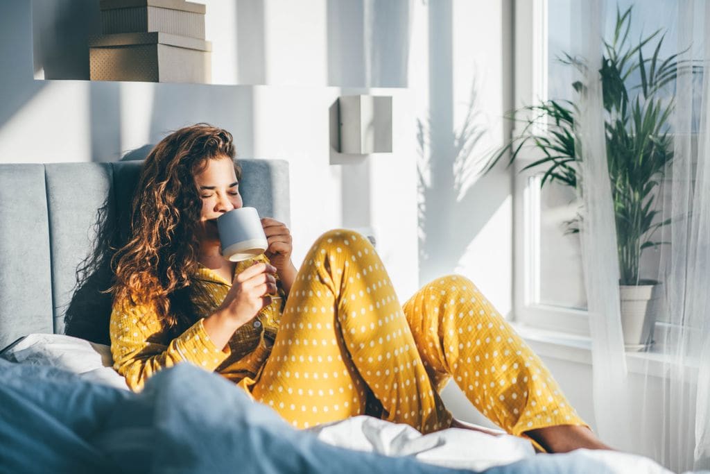 mujer en la cama, tomando un café nada más despertarse