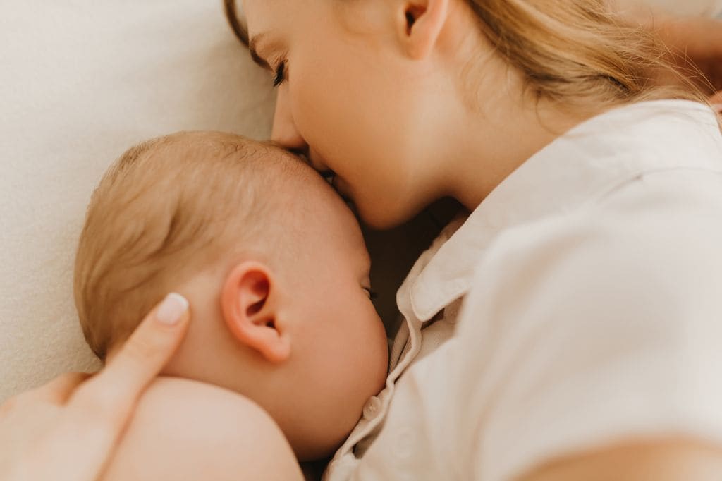 Madre besando a su bebé en la cama